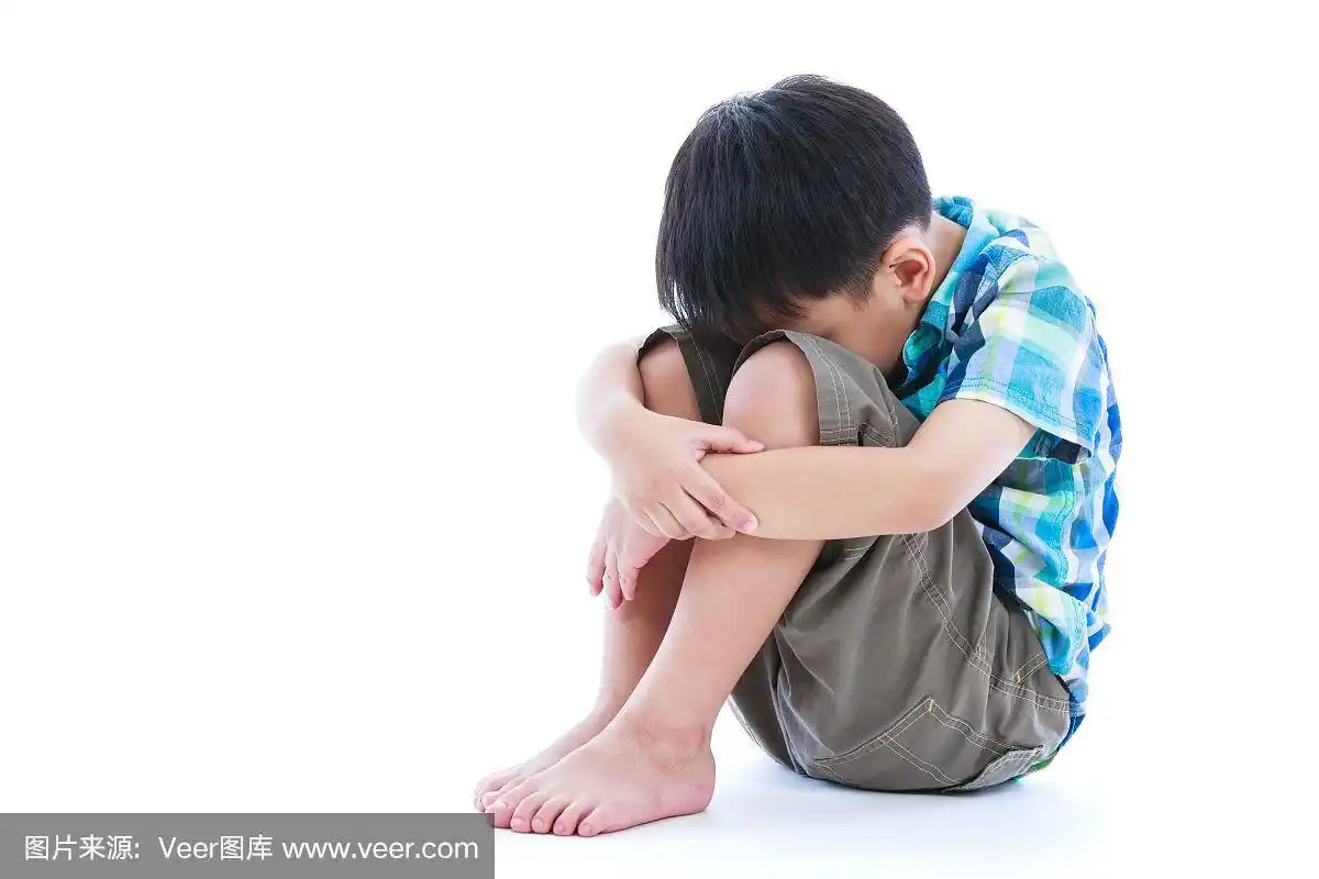 悲伤的男孩赤脚坐在地板上.孤立在白色背景上.