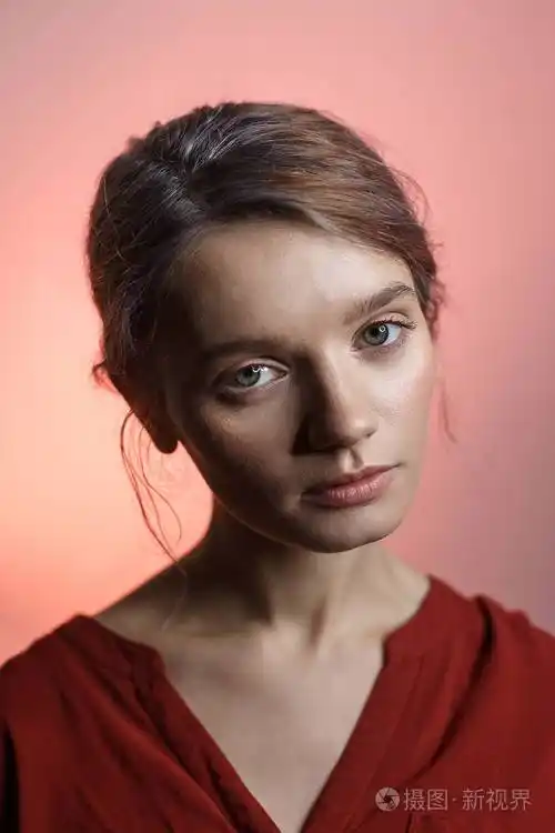 漂亮性感的白人女孩穿着红衬衫看着镜头歪着头粉色背景美女肖像