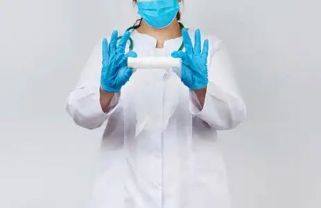 包纱布一名身穿白大褂,戴着口罩的女医务人员拿着一条扭曲的纱布绷带
