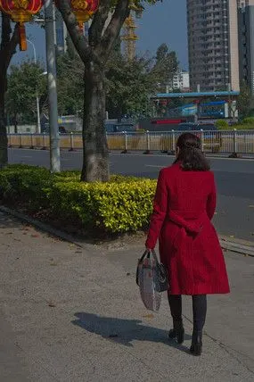 红色风衣女子行走的背影