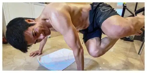 照片中王力宏在家中赤膊做高难度的健身动作,他用双臂的力量将整个