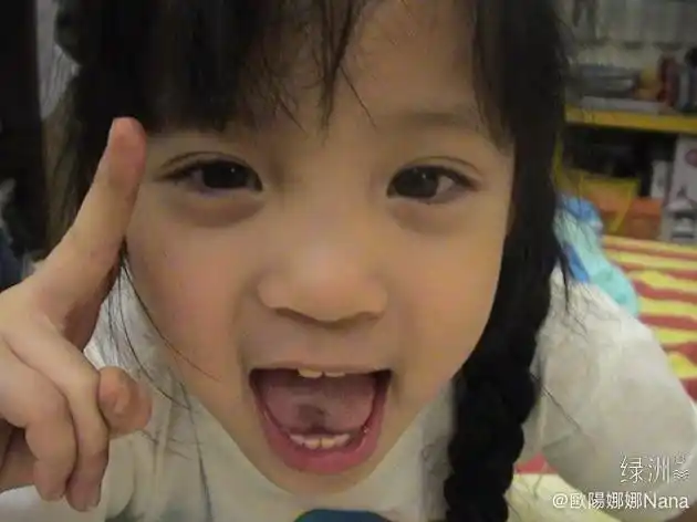 "照片中小欧阳娜娜扎着麻花辫,圆圆脸大眼睛,对镜比耶吐舌,表情鬼马