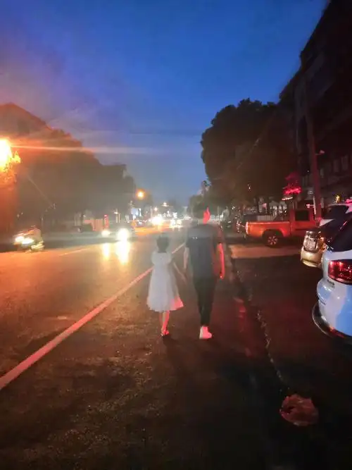 和父亲手牵手漫步在暖灯街道