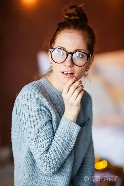 戴眼镜的年轻漂亮女孩的肖像,背景上有圣诞灯