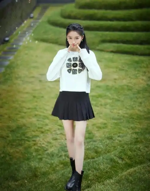 关晓彤梳着俏皮可爱的少女发型,身穿白色卫衣搭配黑色百褶超短裙,脚踩