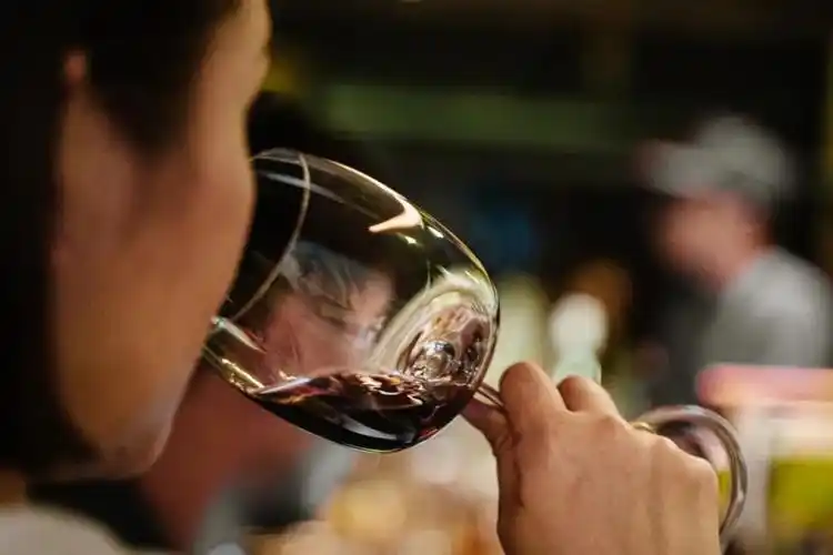 他粗鲁地打开了这瓶酒并倒入纸杯里,然后草率地一饮而尽