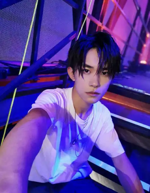 照片中的易烊千玺背对舞台,湿发遮眼,展现出十足的光影感.