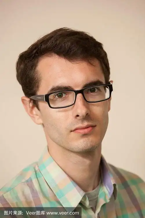 一个30岁的男人戴着眼镜,米色背景上的格子衬衫的工作室肖像