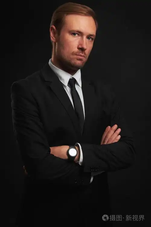 自信英俊的男子穿着黑色西装看着相机