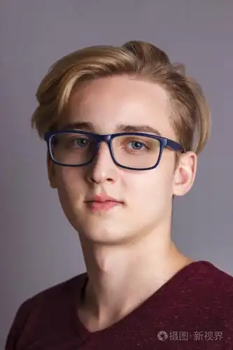 戴眼镜的少年快乐少年在灰色演播室里摆姿势, 合上肖像照片-正版商用