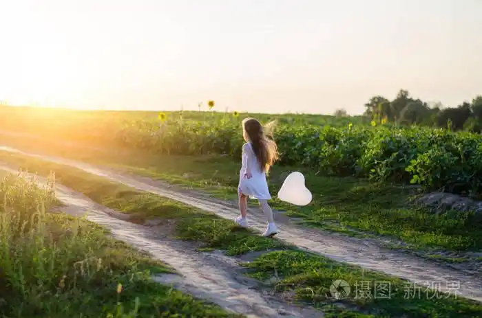 小女孩在草地上的田野里戴着白色的心. 快乐情人节和母亲节的概念.