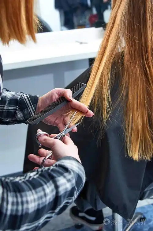 理发师正在与剪刀和梳子.做她的头发的女人金发女郎照片-正版