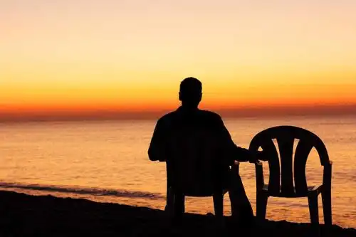 坐在凳子上的穿着破烂衣服的男子