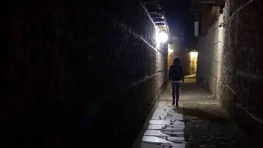 晚上, 孤独的女人走在后街的老石路小巷里照片