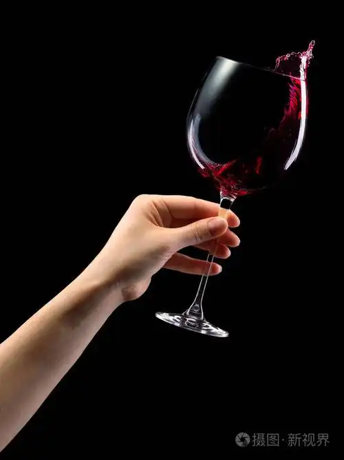 一个女人手拿着红色的酒杯溅起的水花被隔离在黑色上