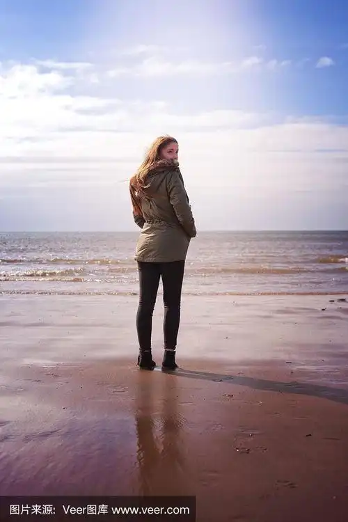 一个站在海滩上的年轻女人的背影