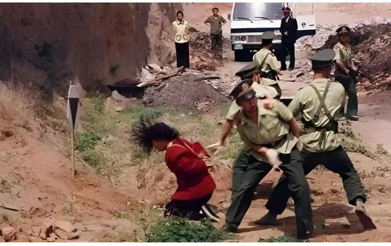 1990年代,一名正在被执行枪决的女死刑犯,画面中的她跪在地上,左右有