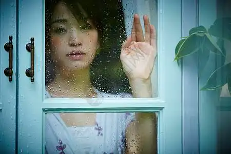 下雨天靠在窗边发呆的孤独女性图片素材