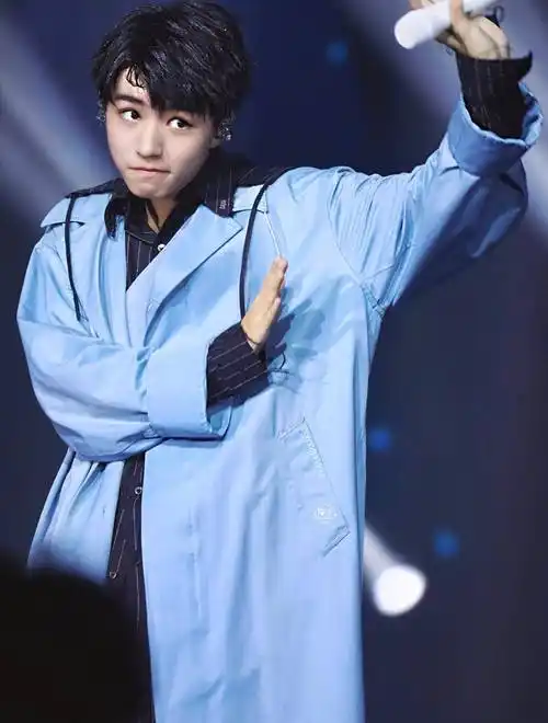 王俊凯上身穿了一件蓝色翻领风衣外套,这件长风衣的款式非常的休闲