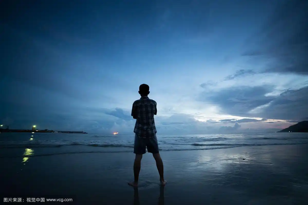 男性背影站在黄昏沙滩上