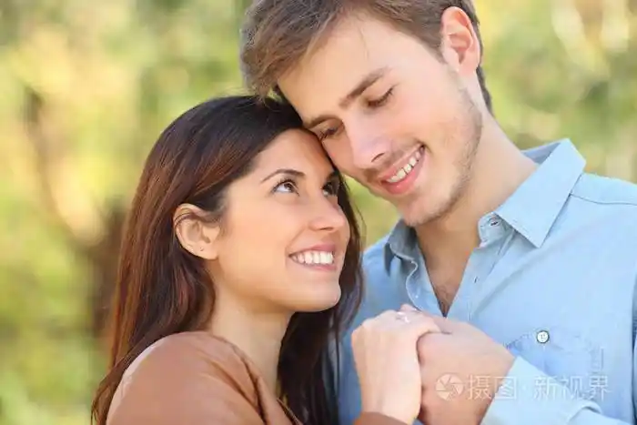 幸福的一对相爱的夫妻,彼此牵手,站在公园里