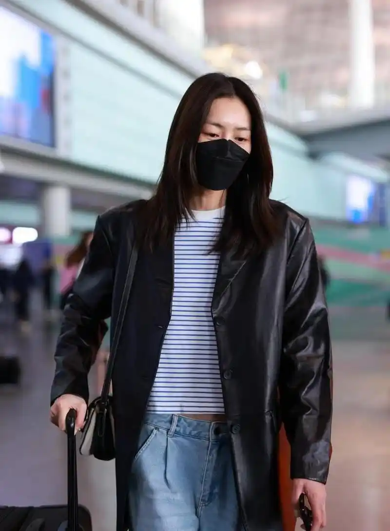 刘雯私服,她穿了一件黑色的皮西装,内搭一件蓝白细条纹的露腰t恤,搭配