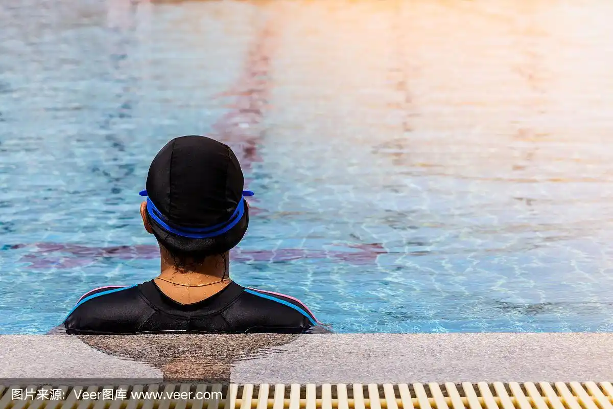年轻女子游泳运动员的背影站在游泳池里.