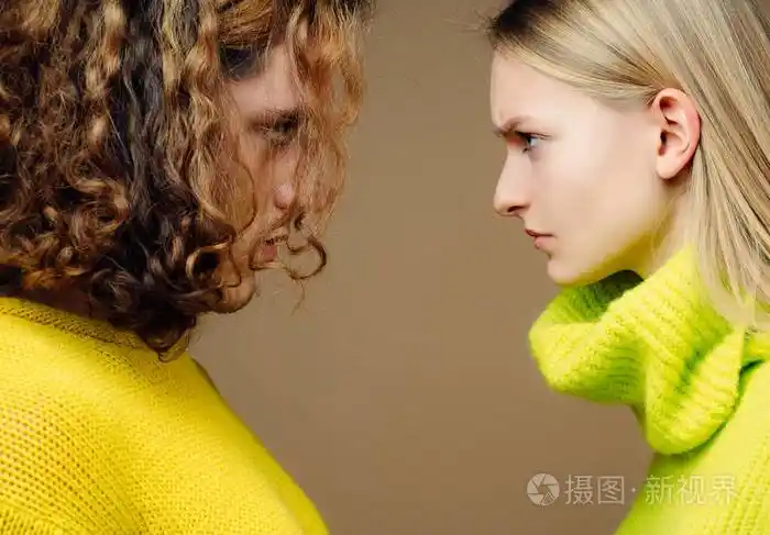 两个严肃自信的年轻人面对面站在一起的特写照片.