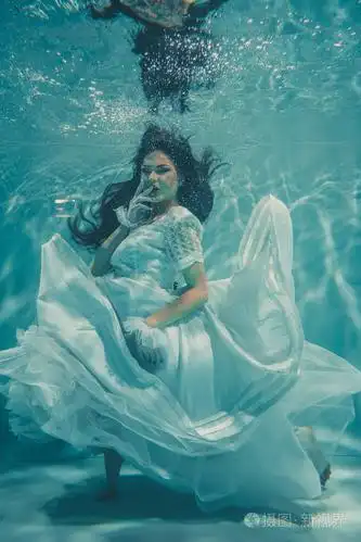 穿着白色婚纱在水下游泳的性感年轻新娘,长袜和手套