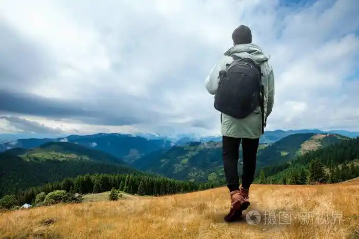 一个男人是巨人,一个男人是一个旅游者,他背着一个背包穿过一个山区