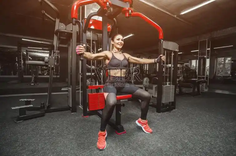 身材苗条的健美女孩在健身房做手臂锻炼照片摄影图片