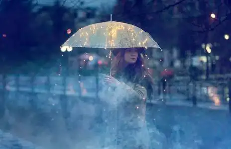 一个女人独自站在雨中,等待着明亮的透明伞照片