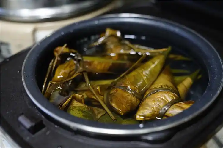 然后将包好的糯米入电饭煲,并加入清水,水量满至粽子,然后选择煲煮