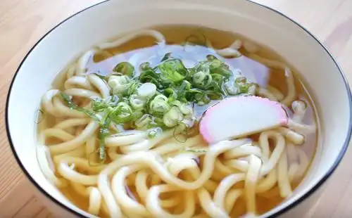 三步做好的汤汁倒入,最后撒入切好的葱花和鱼糕,清汤乌冬面完成第三步