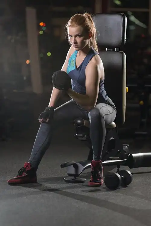 在体育健身房用哑铃锻炼力量的健身运动美女瑜伽普拉提