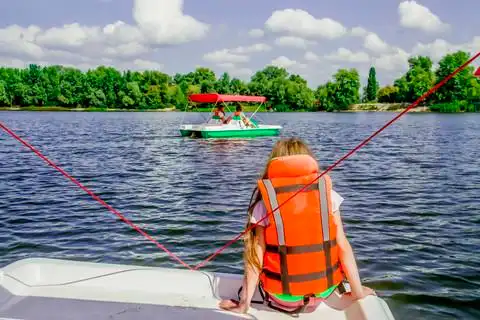 穿着救生衣的女孩背着背坐在船上,享受在河里或湖里游泳的乐趣