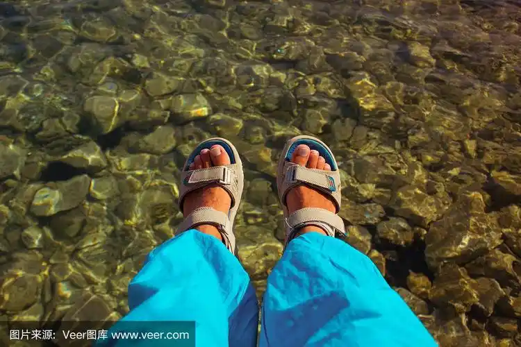 男脚穿凉鞋在湖上绿色的水