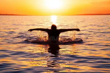 年轻人日出后在海里游泳照片