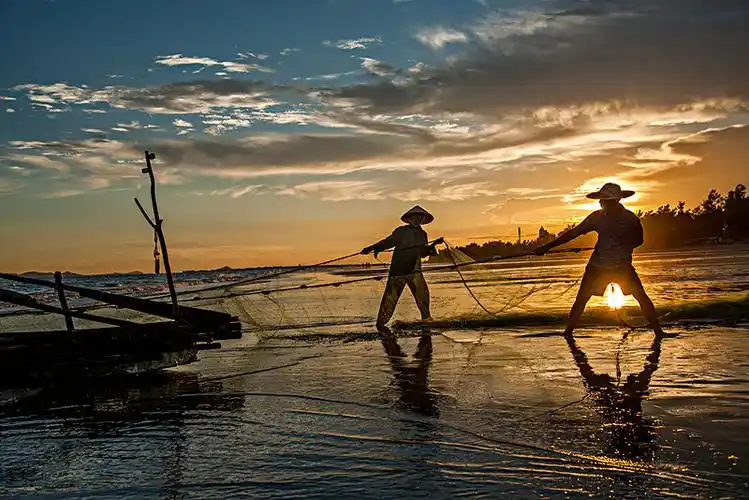 广西东兴京族万尾岛金滩渔民在晚霞中拖网捕鱼