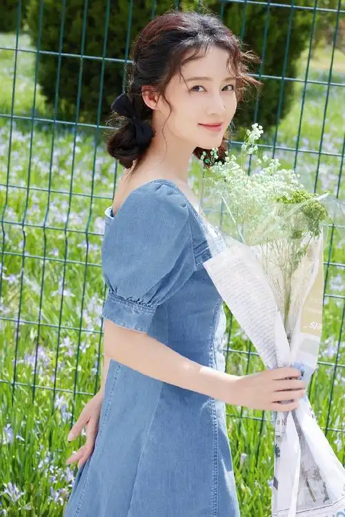 照片中,李沁穿着泡泡袖牛仔裙,手捧花束,回眸浅笑.