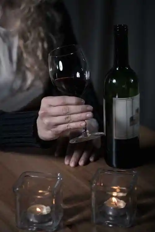 坐在桌子旁边端着酒杯喝酒的女人