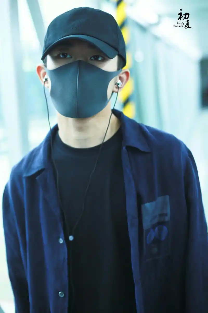 易烊千玺 新闻 小北哥身着黑色内衬和深蓝色衬衫,头戴帽子耳塞耳机