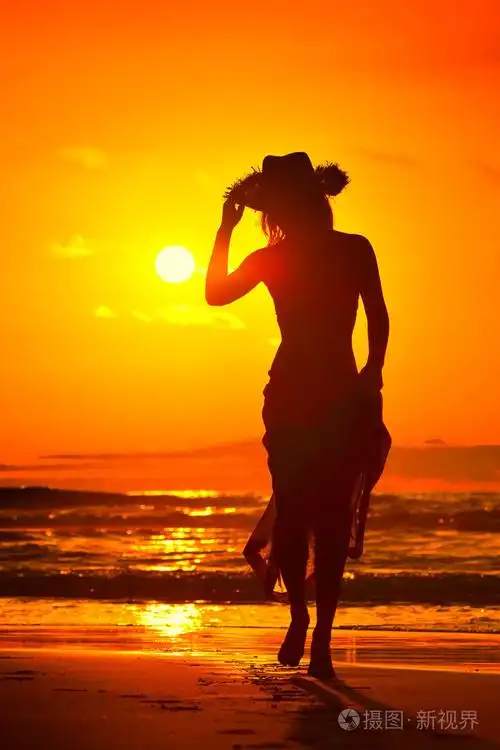 夏日夕阳光在海滩上的年轻女子剪影