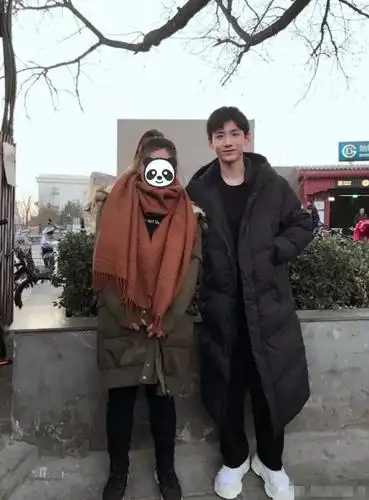 白敬亭穿长款羽绒服与粉丝合照,双手插兜敞着怀很帅气