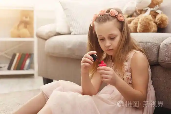 可爱的小女孩抛光指甲坐在地板上