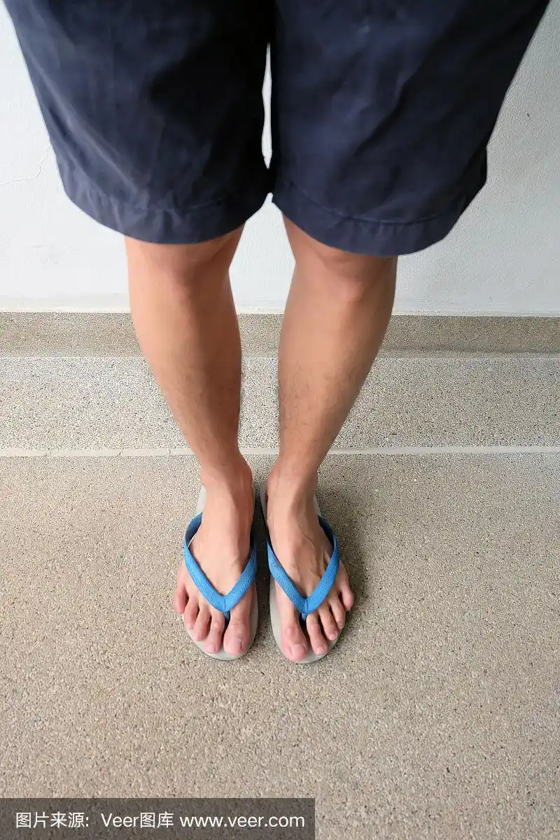 男性的脚和腿近距离穿着蓝色凉鞋皮鞋在水泥路面上.美丽和时尚的概念.