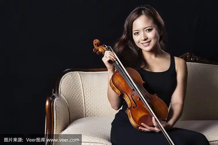 小提琴手拿着小提琴在古董沙发上摆姿势