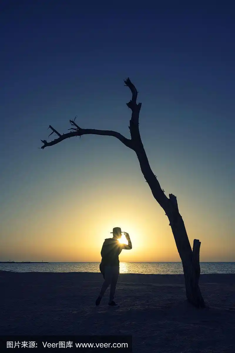 一个人影站在夕阳下的海滩上