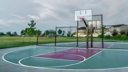 在多云的天空下,在一个公园里的多层家庭住宅附近的全景篮球场照片