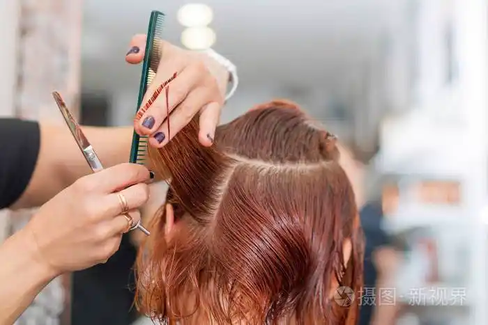 换个新发型的女人女发型师在发廊用剪刀剪头发理发师用手指夹住发夹